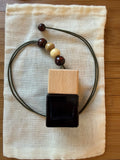 Necklace with beads and a square pendant on a textured fabric surface
